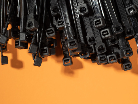 Plastic black ties on an orange background. Plastic ties for cables.