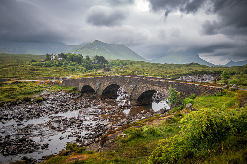 Sligachan Old Bridge with moody dark clouds on a gloomy day in the Scottish Highlands.
