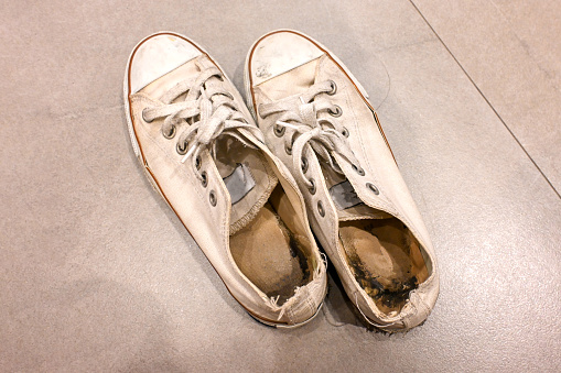 Old and dirty white cream canvas sneakers.