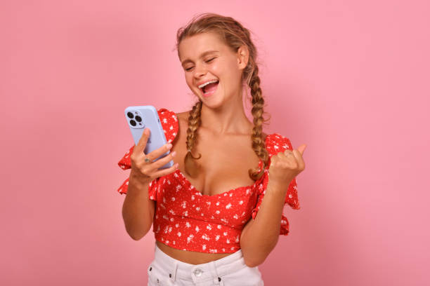 istock Young overjoyed Caucasian woman with phone makes winning gesture 1585278879