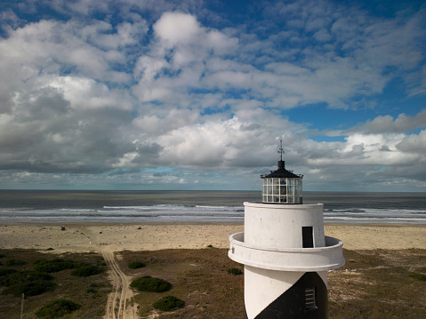 The Flamborough head lighthouse captured behind tall grass against the blue sky with clouds