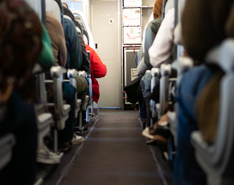 empty aisle of plane full of seated passengers