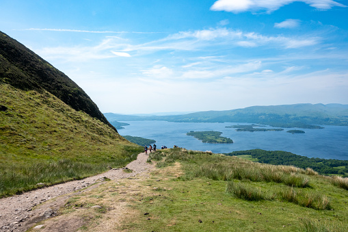 Balmaha, Scotland - June 10, 2022: Hikers on the West Highland Way in the Scottish Highlands on Conic Hill above Loch Lomond.