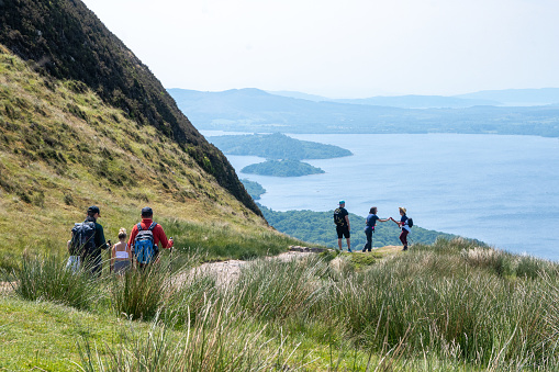 Balmaha, Scotland - June 10, 2022: Hikers on the West Highland Way in the Scottish Highlands on Conic Hill above Loch Lomond.