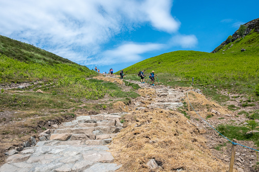 Balmaha, Scotland - June 10, 2022: Hikers on the West Highland Way in the Scottish Highlands descending Conic Hill.