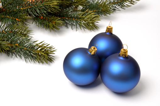Three blue Christmas baubles in front of a fir branch