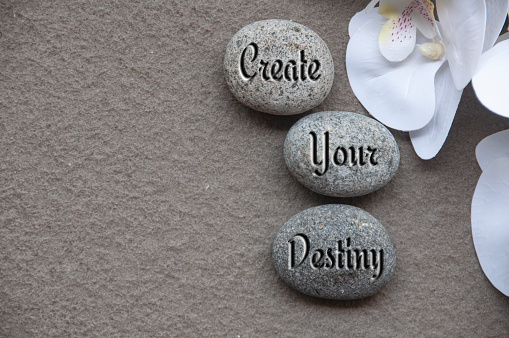 Top view of motivational quote text on rocks - Create your destiny.