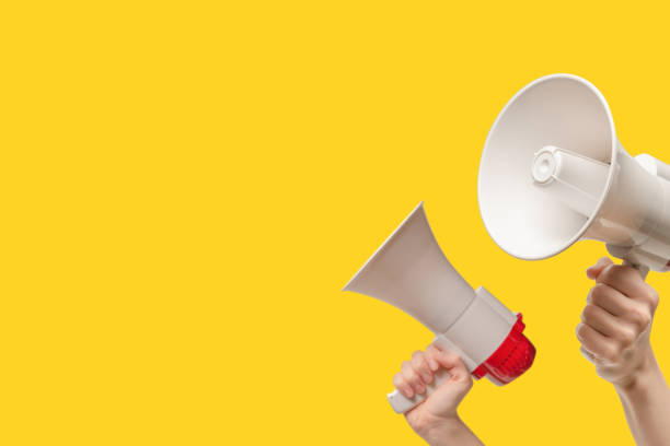 istock Megaphone in woman hands on a yellow background. 1585328718