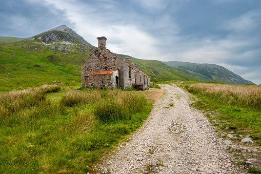 View of the West Highland Way in the Scottish Highlands with an abandoned farmhouse.