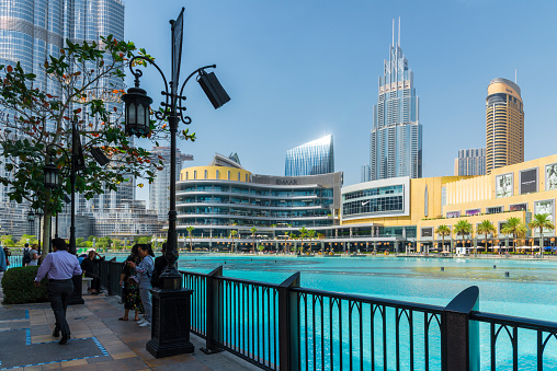 Dubai UAE - March, 14. 2019 - the highest building of the world - Burj Khalifa. Photo taken from public ground in front of the shopping mall with tourists. Here the artifical lake area around the Burj Khalifa with fountain attractions every half hour.