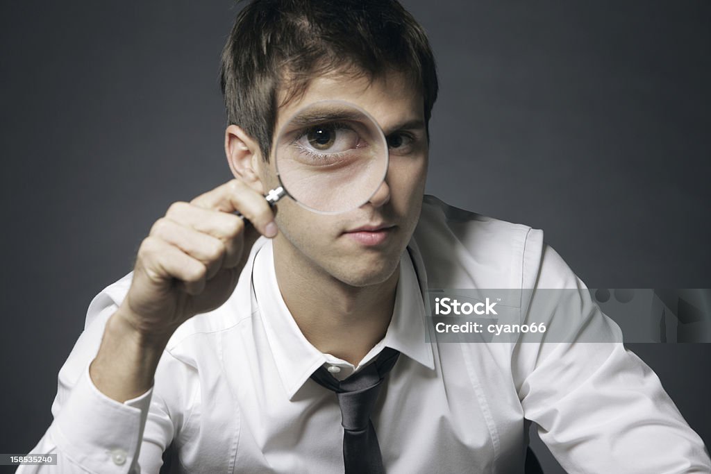 Analyze the business businessman looking through a magnifying glass Adult Stock Photo