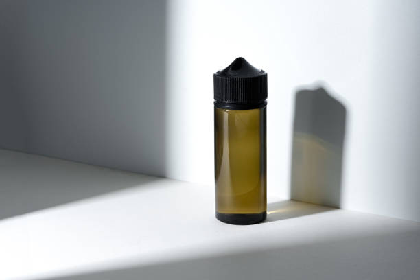 istock Dropper bottle with vape liquid on white background in the sunlight with shadows 1585369639