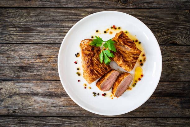 istock Roast pork loin in sauce  on wooden table 1585376382