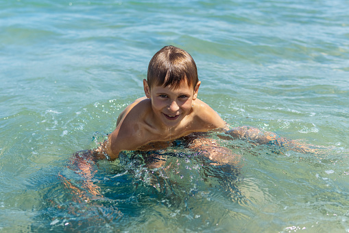 Happy boy swims and dives under water Active healthy lifestyle, water sports, seascape with a child there is a place for an inscription