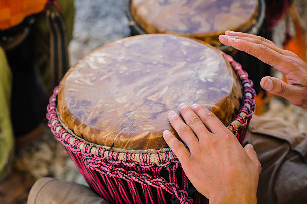 A man playing the djembe between his knees stock photo