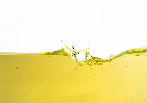 Beautiful wave of yellow base oil against a pristine white background, creating an alluring visual representation of its significance in the automotive and industrial businesses. The transparent, liquid gold-colored base oil flows gracefully, evoking a sense of motion and freshness, making it a vital lubrication source for engines and various applications.