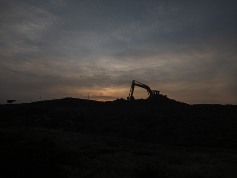 silhouette of heavy excavator over dugout