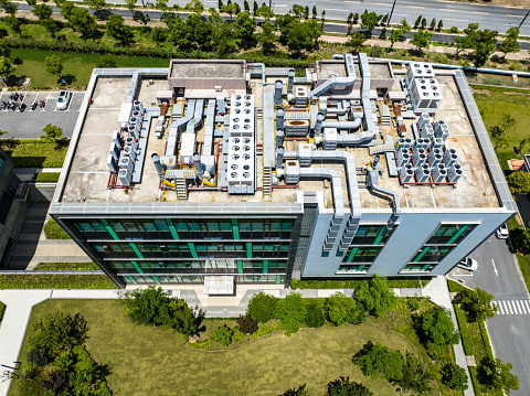 High angle view of cooling extractor fans and pipes on a commercial air-conditioning system on an inner city rooftop. Exhaust vents on the roof of a tall building.