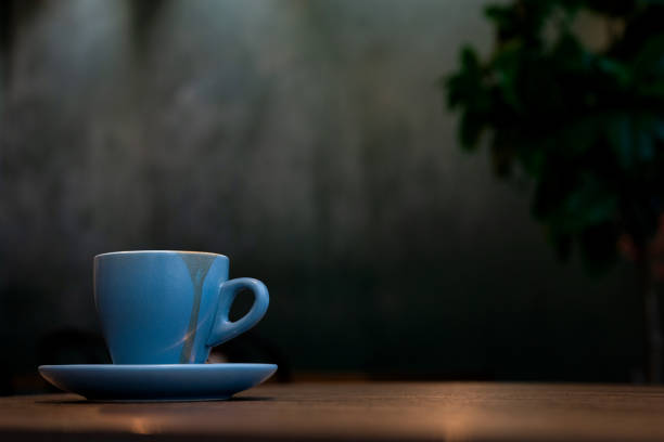 istock Coffee in blue cup on wooden table in cafe with lighting background 1585403532