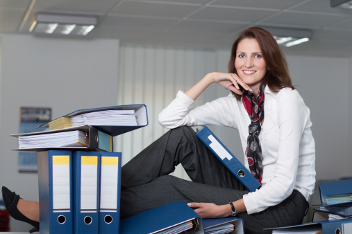 Businesswoman sits on the table surrounded by many files