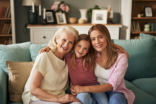 Portrait of grandmother, little girl and young woman holding ultrasound picture