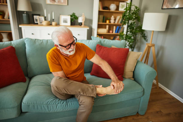 älterer mann, der händchen am knöchel hält und unter schmerzhaften gelenkschmerzen leidet - arthritis senior adult rheumatoid arthritis sadness stock-fotos und bilder