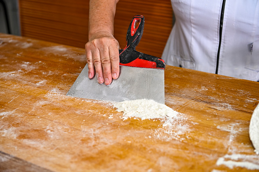 Baker cleaning the table from flour