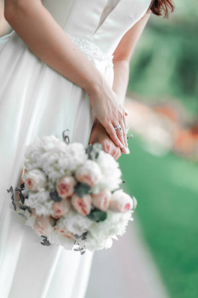 istock close up. the bride holds the wedding bouquet behind her back. 1585425504