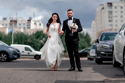 happy bride and groom walking down the street in the big city. holidays and events