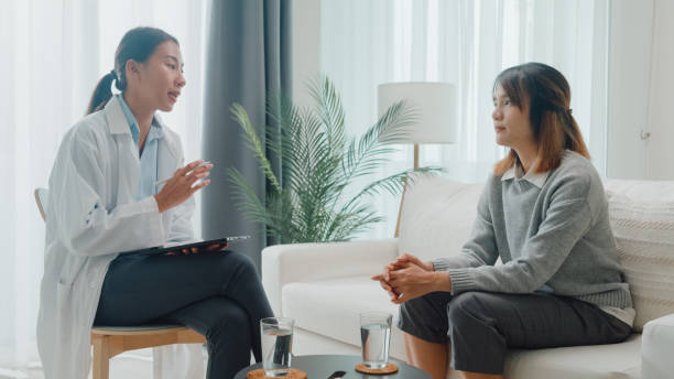 Young Asian female psychotherapist using digital tablet discussing a problem and stress with patient sit on couch at clinic. Medical insurance, Mental health. Young Asian female psychotherapist using digital tablet discussing a problem and stress with patient sit on couch at clinic. Medical insurance, Mental health concept. melancholy computer support specialist stock pictures, royalty-free photos & images