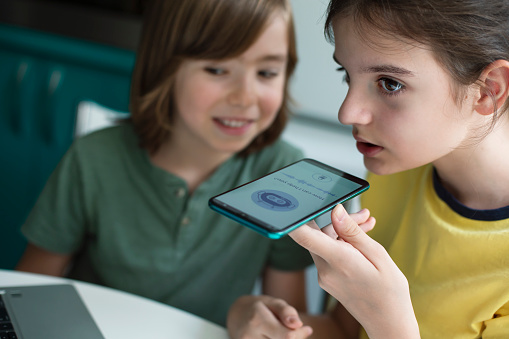 Two happy children using system AI Chatbot in computer or mobile application. Chatbot conversation, Ai Artificial Intelligence technology. Open AI generate. Futuristic technology. Virtual assistant on internet.