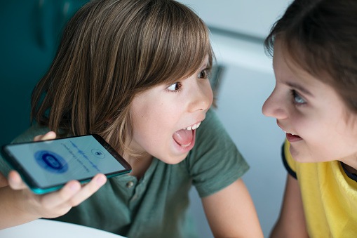 Two happy children using system AI Chatbot in computer or mobile application. Chatbot conversation, Ai Artificial Intelligence technology. Open AI generate. Futuristic technology. Virtual assistant on internet.