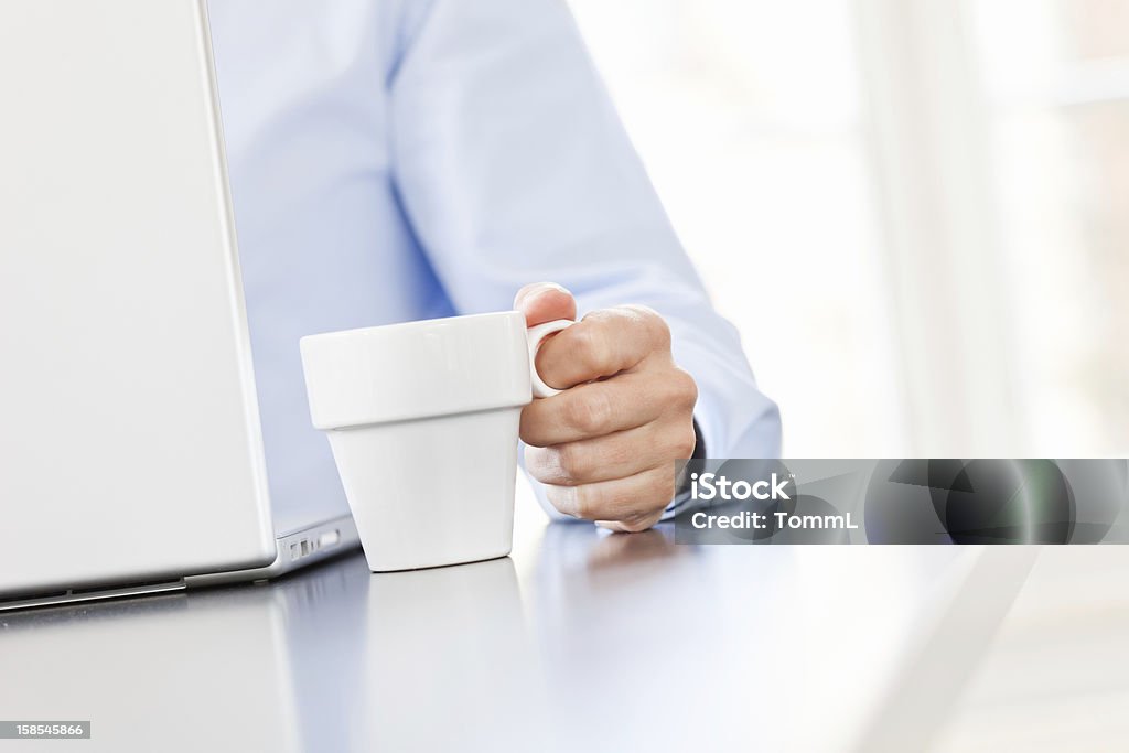Ein Mann im blauen Hemd holding auf die cup und computer durchsuchen - Lizenzfrei Arbeiten Stock-Foto