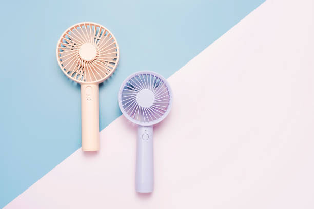 istock Small portable mini fans on blue and pink background close-up. 1585466618