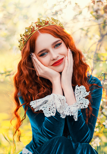 Close-up portrait happy red-haired woman queen in golden crown on head looking at camera. Girl joyful cheerful princess smiling face, green renaissance victorian dress. Red lips pale skin long hair.