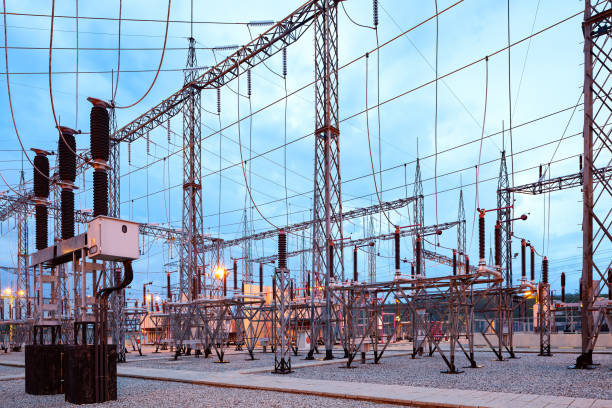 Illuminated electricity substation at dusk.