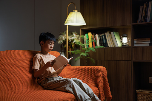 A little boy reads at home at night