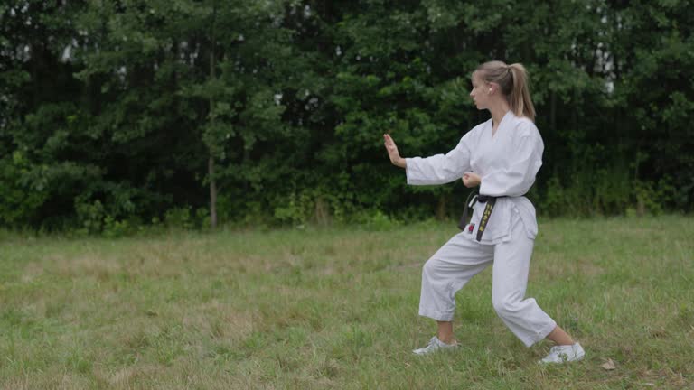 Teenage girl practicing karate on the meadow