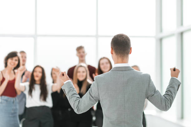 istock rear view. business man looking at a group of diverse young peo 1585500726