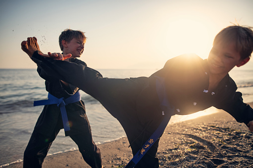 Little boys practicing kung fu on the beach. Boys are fighting.\nShow with Nikon D850