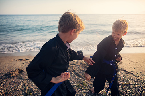 Little boys practicing kung fu on the beach. Boys are fighting. 
Show with Nikon D850