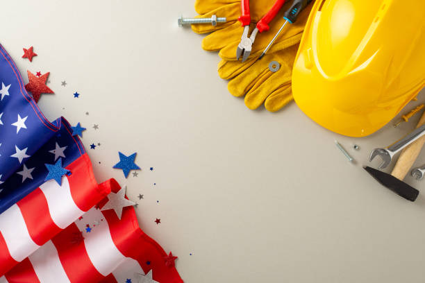 Capture attention with this construction-themed top-view image, showcasing a flag, work helmet, gloves, and tools on a light grey backdrop. Great for Labor Day campaigns, messages, or text placement capta la atención con esta imagen de vista superior con temática de construcción, que muestra una bandera, un casco de trabajo, guantes y herramientas sobre un fondo gris claro. ideal para campañas, mensajes o colocación de texto del día del trabajo
