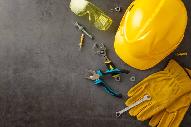 Paying tribute to hard work of construction workers on American Labor Day. Above shot of helmet, gloves, safety glasses and building tools on grunge textured grey concrete. Suitable for ads or text rindiendo homenaje al arduo trabajo de los trabajadores de la construcción en el día del trabajo americano. arriba toma de casco, guantes, gafas de seguridad y herramientas de construcción en hormigón gris con textura grunge. adecuado para anuncios o t
