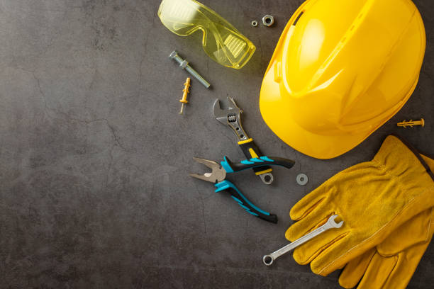 アメリカ労働者の日に建設労働者の努力に敬意を表します。上のショットは、グランジテクスチャの灰色のコンクリートにヘルメット、手袋、安全メガネ、建築工具を描いています。広告や� - adjustable pliers ストックフォトと画像