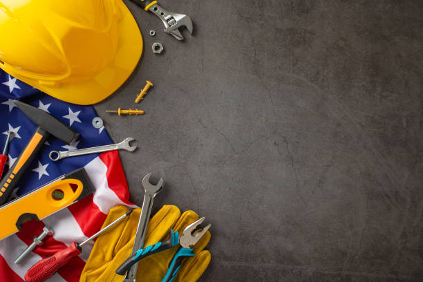 istock Honoring the dedication and skill of construction workers on Labor Day. Overhead view photo featuring flag, hard hat, gloves and tools on grunge textured grey concrete. Copyspace for ads or text 1585529761