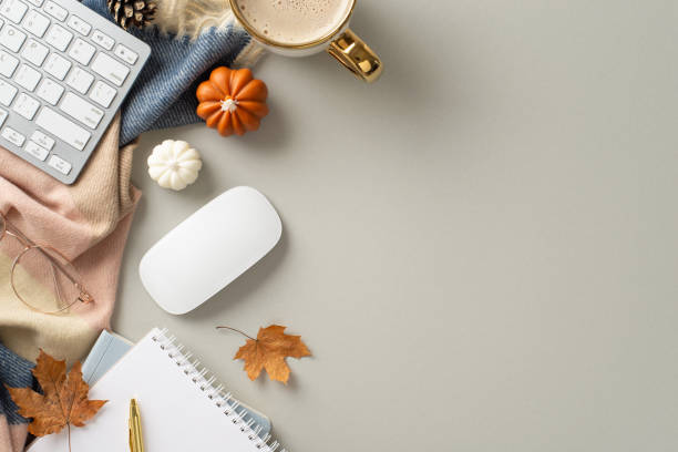 istock Fall-themed work setup: top-down snapshot showcasing notepad, elegant pen, glasses, keyboard, mouse, steaming coffee, patterned scarf and maple leaves on grey backdrop. Ample copyspace for text or ads 1585533093