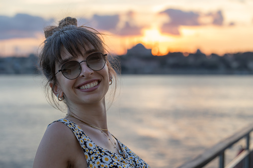 Young woman is traveling around city of Istanbul on ferry at sunset.