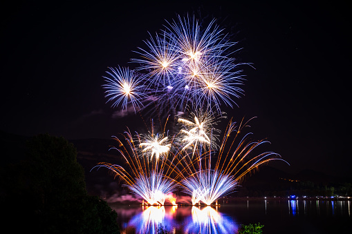 Colorful fireworks during national holiday celebrations in France, Bastille day. This fireworks was shot over Rhone river in Montalieu-Vercieu city in Isere, Auvergne-Rhone-Alpes region in France, Europe.