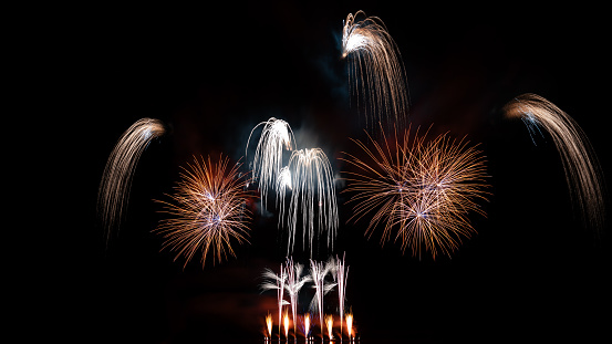 Beautiful colorful red and orange holiday fireworks on the black sky background