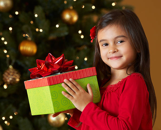 istock Girl Holding Christmas Present In Front Of Tree 158554501